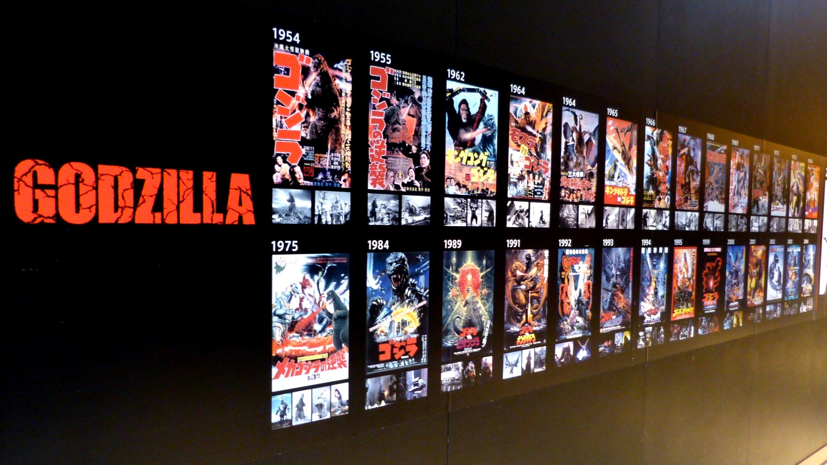 godzilla movie posters line a hallway, except for the US film